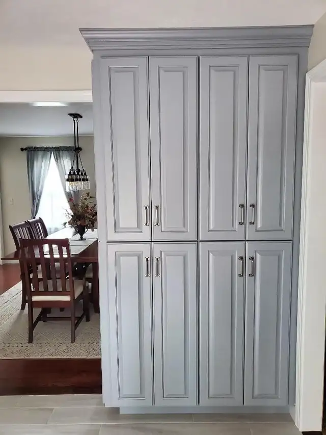 Tall gray painted pantry cabinets with bar pulls beside a dining area