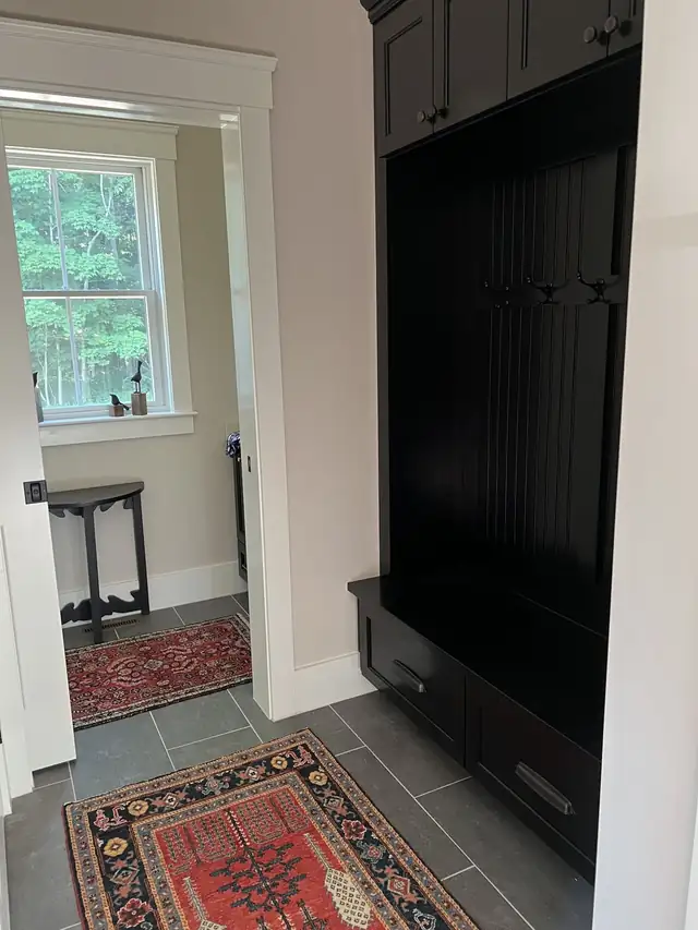 Black built-in mudroom bench with hooks beside a doorway